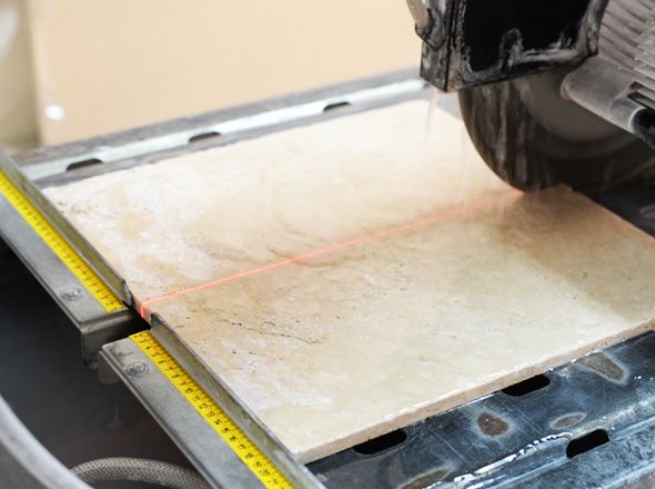 Een zaag zaagt lichtgekleurd natuursteen