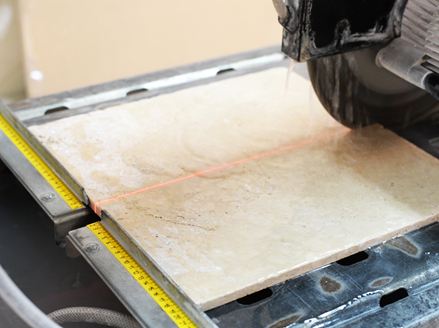 Een zaag zaagt lichtgekleurd natuursteen