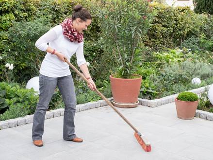 Vrouw maakt graniet grijs terras schoon