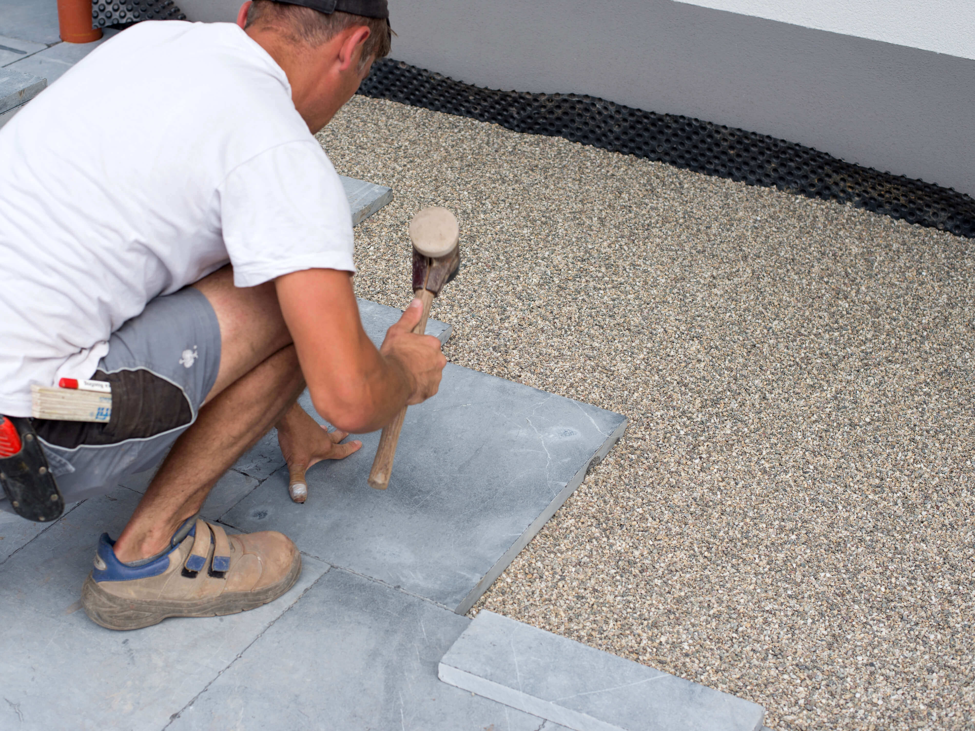 Man legt arduinen platen in een bed van steenslag