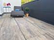 Balkon met ligstoel en terrastegels van houtlook keramische tegels als vloerbedekking