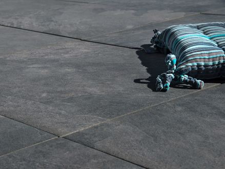 Kussen ligt op donkergrijze Alpine Black keramische tegels