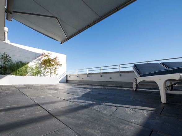 Dakterras met leisteenvloer en ligstoelen aan de rand met kikkeruitzicht