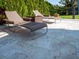 Twee ligstoelen op travertin terras Medium met haag erachter