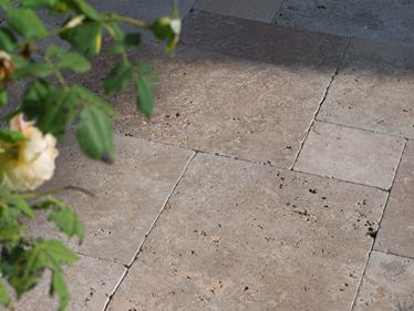 De late namiddagzon speelt op de terrasvloer, takken steken van rechts in het beeld