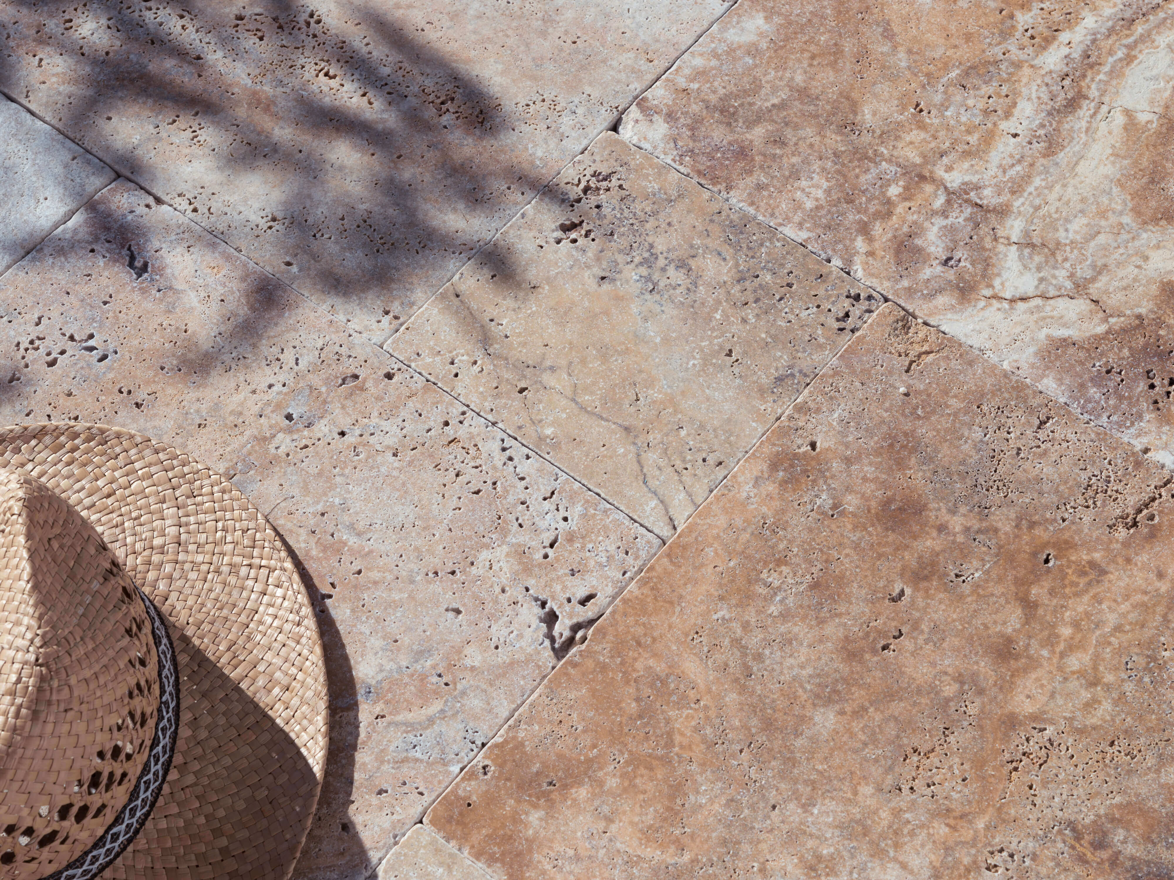 Travertin Scabas terras in zonlicht met strohoed