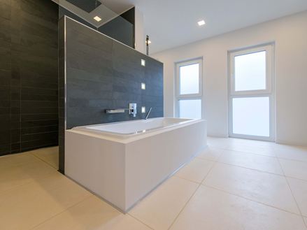 Badkuip op lichtgekleurde kalkstenen tegels en leisteen als wandbekleding