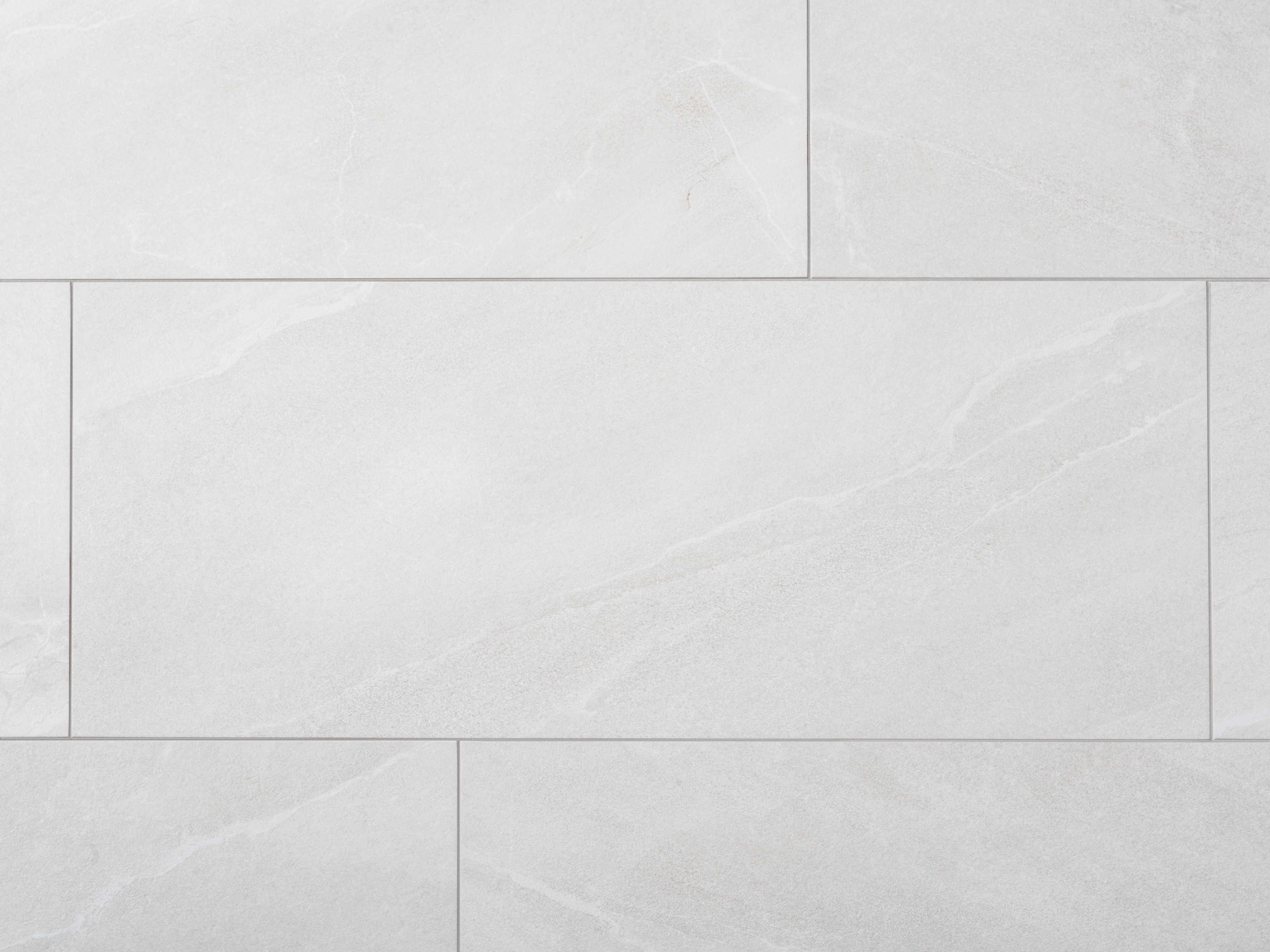 Close-up van lichtgrijze keramische tegels met leisteenlook en smalle voegen