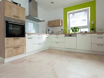 Keuken in wit met houten elementen en groen raamkozijn op Lichte travertin tegel met getrommeld, niet geÃ«galiseerd oppervlak