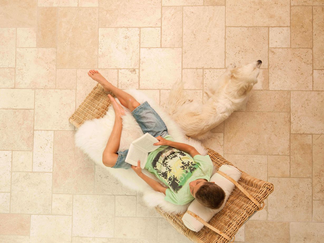 Levendig wonen in mediterrane stijl Lezende jongen in een ligstoel op lichte travertin tegels gelegd in Romeins verband