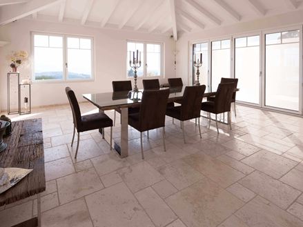 Eetkamer met hoog plafond, tafel en stoelen op travertin Licht in Romeinse binding
