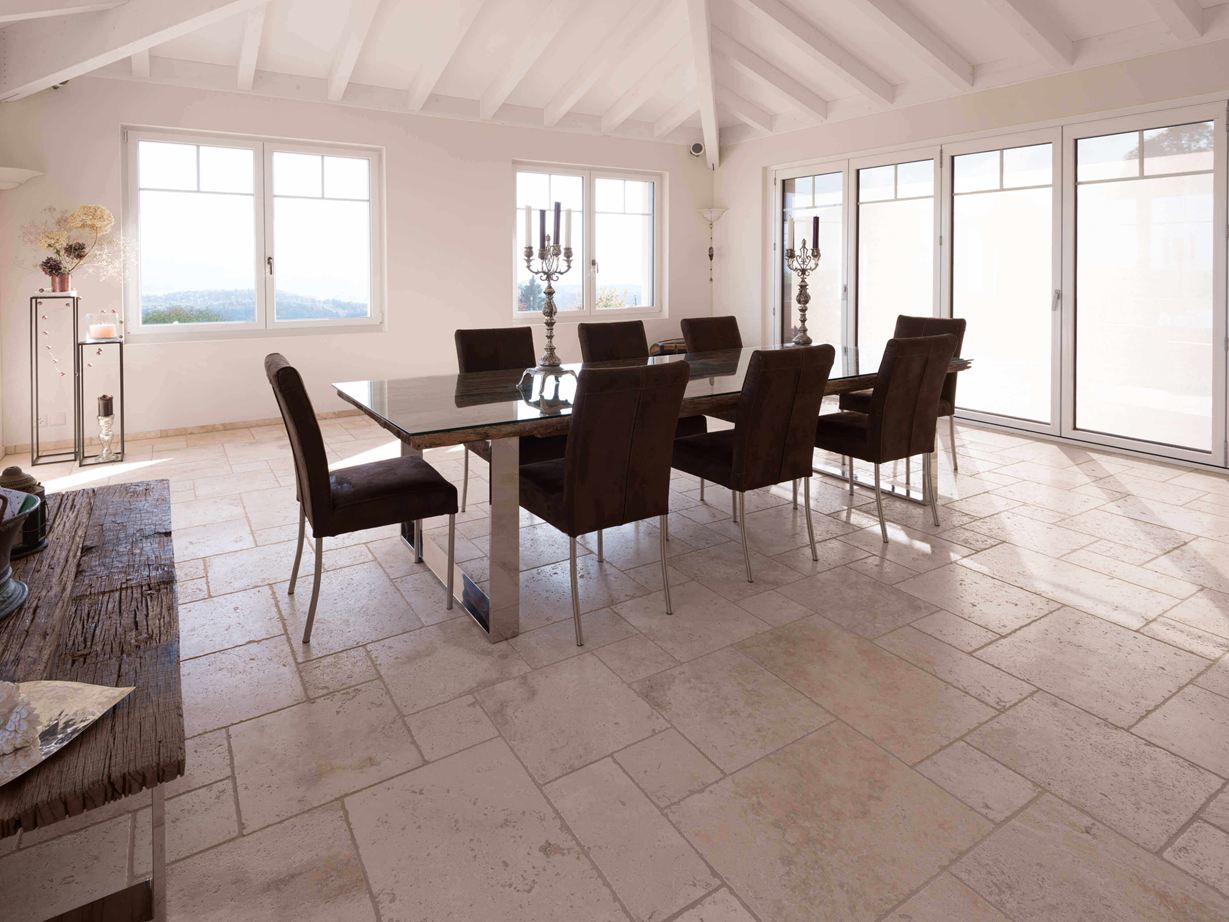 Eetkamer met hoog plafond, tafel en stoelen op travertin Licht in Romeinse binding