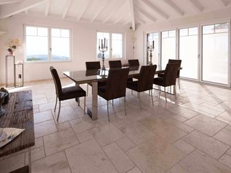 Eetkamer met hoog plafond, tafel en stoelen op travertin Licht in Romeinse binding