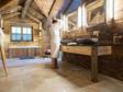 Badkamer met veel hout en travertin, vrouw staat in badjas voor spiegel