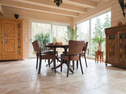 Eethoek met houten banken en rustieke travertin vloeren