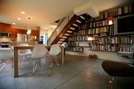 Moderne woonkamer op betonnen vloer met grote boekenkast op de achtergrond