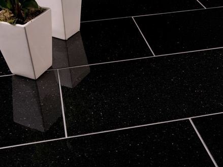 Twee witte bloemperken op donkere Star Galaxy granieten tegels met smalle, lichtgekleurde voegen