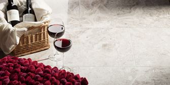 Twee wijnglazen staan naast een gevulde mand met aardbeien op gepolijste Silver Shadow marmeren tegels