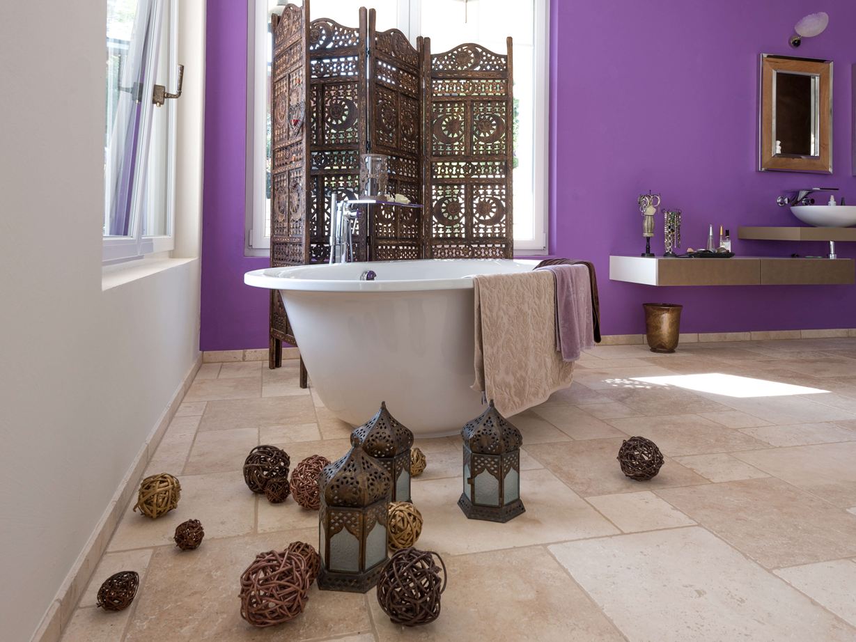 Travertin Lichte tegels in een badkamer met vrijstaand bad en paarse muur op de achtergrond