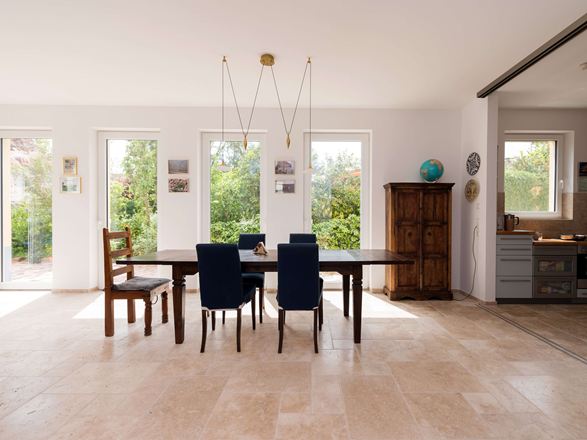 Lichte eethoek met houten meubels en beige travertin tegels als vloerbedekking