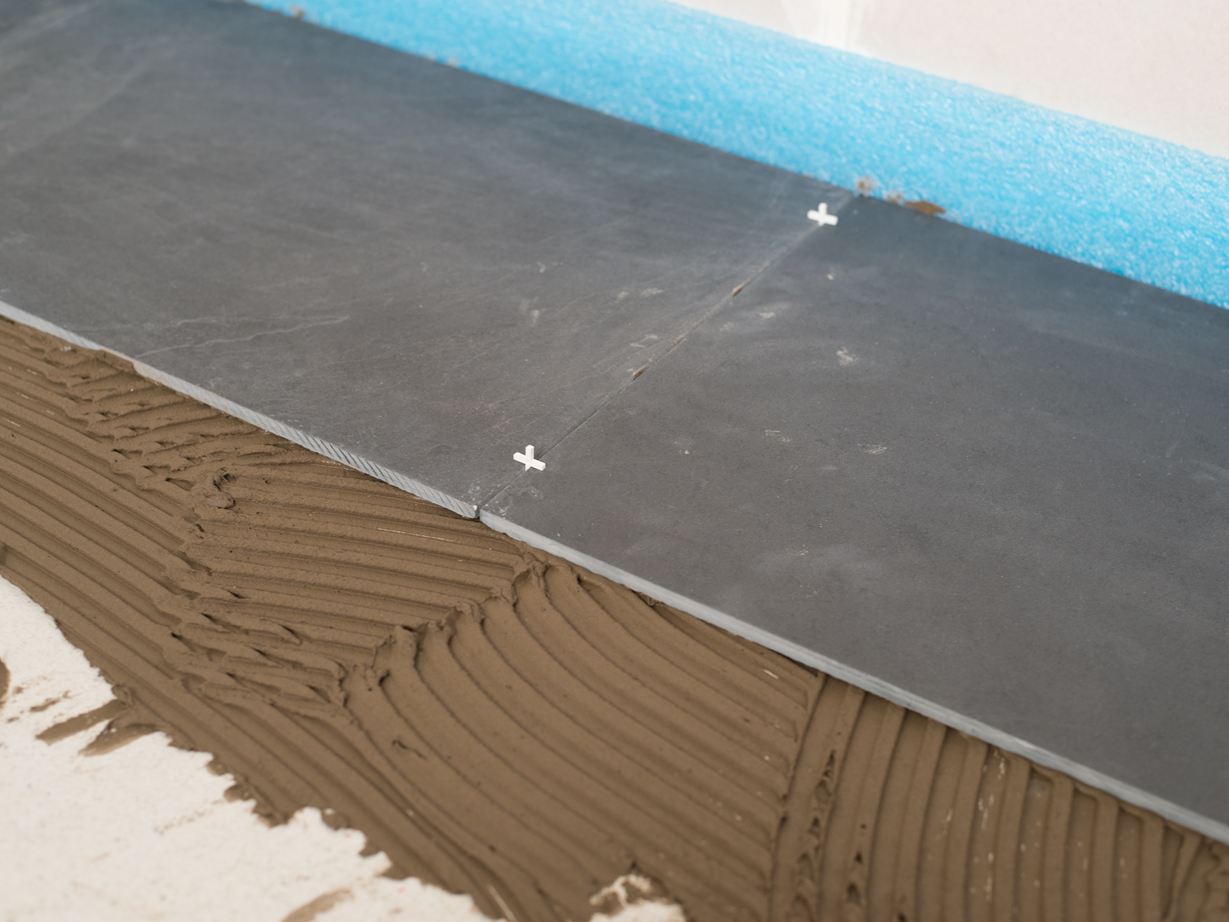 Voegen met kruizen als afstandhouders tussen twee leistenen tegels