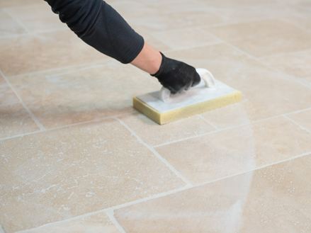 Voegen worden met een spons van gelegde travertin tegels afgewassen.