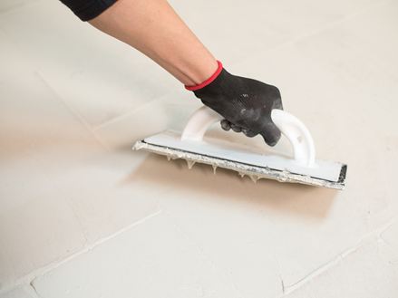 Met één hand een travertijnen vloer voegen