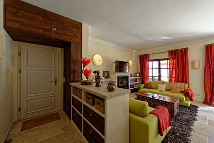 Woonkamer in mediterrane stijl met groene bank en rode gordijnen